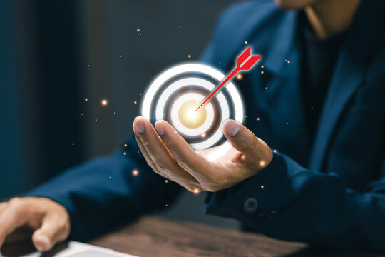 Businessman holding glowing target icon with arrow, symbolizing goal achievement, strategy planning, business success, motivation, and effective corporate leadership.
