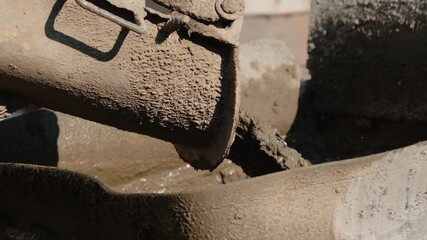 The concrete mixer is pouring wet cement at a construction site - Powered by Adobe