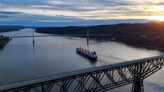 Aerial view of the Mid-Hudson Bridge and the Franklin D. Roosevelt Mid-Hudson Bridge spanning the Hudson River as a cargo ship navigates the waters, Poughkeepsie, New York, United States.