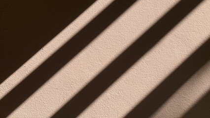 Fototapeta premium Abstract pattern of geometric striped shadows and natural sunlight falling dramatically on a textured white concrete wall background with empty copy space.