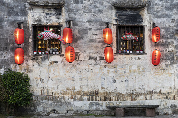 Aerial view of red lanterns casting a warm glow against the ancient stone walls, illuminating fish decorations in windows, Hongcun Village, Anhui, China.