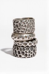 A set of four wide, textured sterling silver rings with various hammered and rough organic patterns, arranged vertically on a plain white background