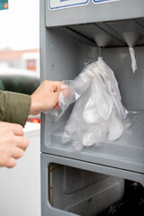 A man at a gas station takes disposable plastic gloves before refueling his car, showing attention to cleanliness, hygiene, and preparation for safe handling of fuel