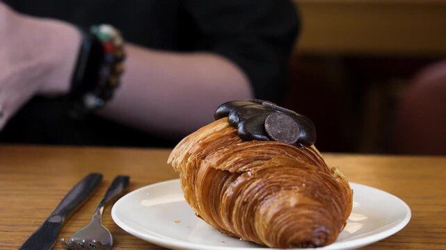 A hand reaches for the chocolate croissant