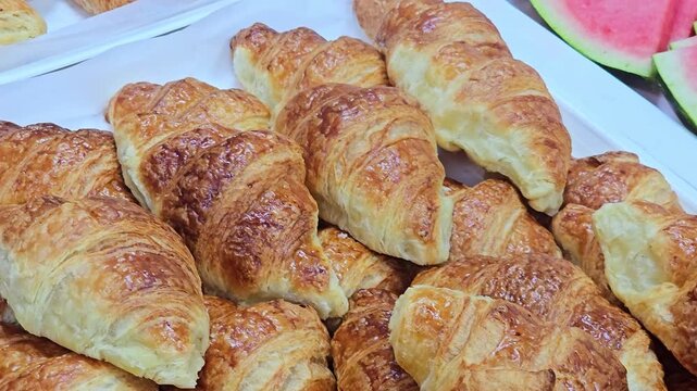 ​Close-up of a generous pile of perfectly golden-brown, flaky, and buttery French croissants, hot from the oven. Ideal for food, bakery, or breakfast visuals. 4k video