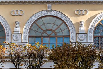 Large arched window against a yellow wall with a bas-relief and white sculptures arranged symmetrically on both sides. From the Mira window series.