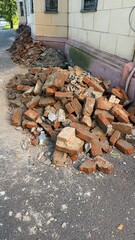 Stack of broken bricks and rubble on a street next to a building corner