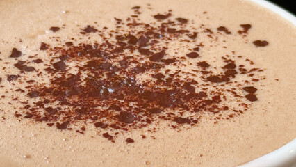 Hot chocolate with cocoa powder sprinkled on foamy surface, perfect for cozy holiday background