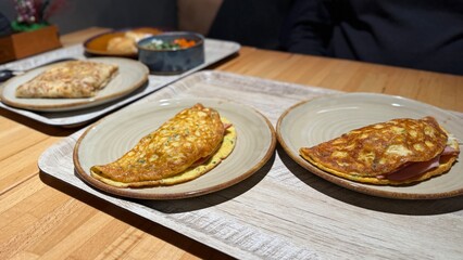 Omelets served on plates with assorted accompaniments on wooden table in restaurant setting