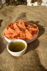 Bowl of Fresh Raw Carrot with Olive Oil on Sackcloth Background, Top View