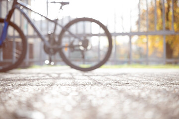 Blurred background with bicycle on the street near the fence, lifestyle concept with sun rays and glare.