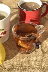 Two cups of tea with lemon and berries on a linen tablecloth