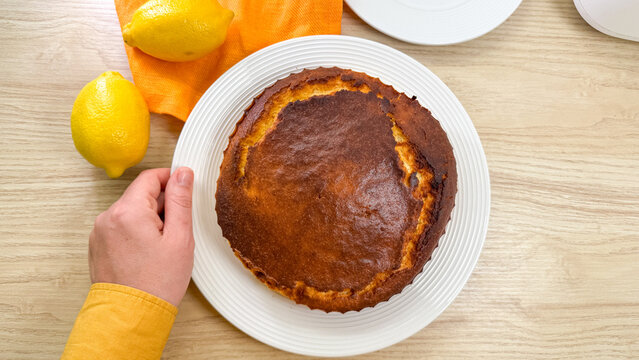 Aromatic lemon cake embraced by a curious hand, embodying citrus zest festivities and quirky baking rituals of Lemon Meringue Day