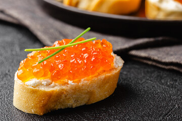 Single canape with red caviar and chives garnish