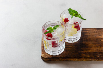 Raspberry cocktails with ice in a glass on a light background