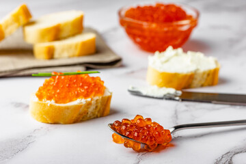 Caviar sandwich composition with spoon and knife on marble