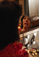 A woman is applying lipstick at home