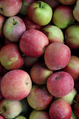 Heap of fresh red and green apples close-up. Natural fruit background with ripe organic apples, healthy food concept, and harvest season texture.