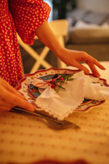 the hand of a woman setting the table for Christmas dinner