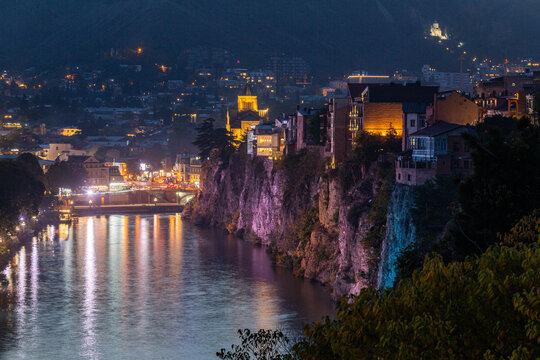 A view of Tbilisi at night: the high bank of the Mtkvari (Kura) River, the Metekhi Church, traditional Georgian houses, and beautiful lighting.