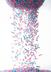 Naklejka premium Falling pink and blue sprinkles create a visually appealing, vibrant spectacle. These colorful sprinkles are scattered