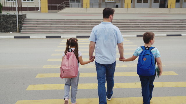 Family Morning by School, Dad Walks Kids Safely, Children Head to Class, Street Awareness Lesson, Parent and Children Bond, School Bags Packed, Starting Education Journey, Zebra Crossing in Town
