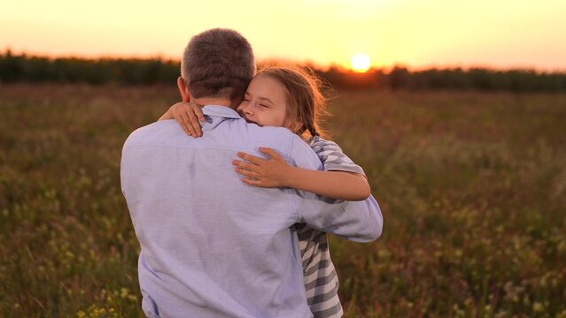 Father man hugging happy daughter child sunset, Father and daughter hug at sunset, Close family bond outdoors, Emotional embrace in nature, Loving father and happy child, Warm sunset in the field