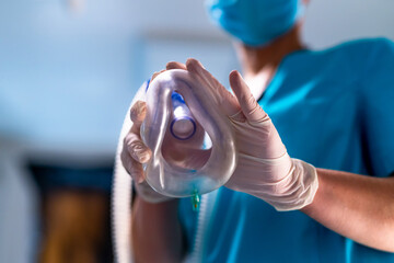 Anesthesia mask in hands. Gloved hands hold an anesthesia mask during clinical preparation.