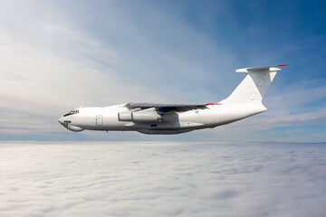 White wide body freight cargo airplane fly in the air above the clouds