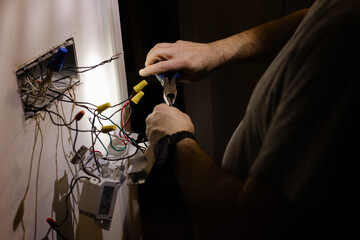 Electrician working on wiring in a dimly lit room during the evening