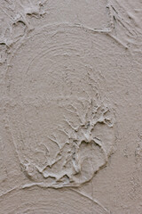 Textured wall with circular patterns and smooth finish in neutral tones during daylight