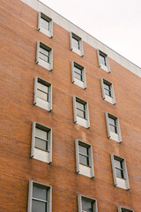 Fototapeta premium Modern brick building with symmetrical windows under a cloudy sky in an urban setting