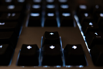 Close-up on the glowing arrow keys of a backlit keyboard. The 'up' arrow is in focus, symbolizing progress and navigation. Moody, high-tech aesthetic with beautiful bokeh.
