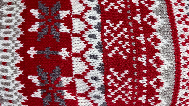 Cozy knitted background with red, white, and gray traditional Scandinavian Fair Isle pattern texture