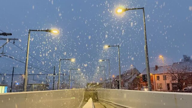 Snowflakes dance under street lights on a winter evening with soft city sounds filling the air