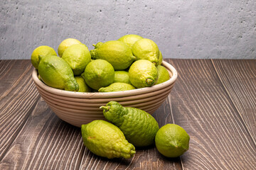 Fresh green lemons in a wicker bowl on wood