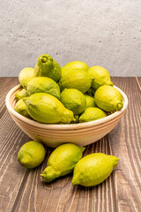 Fresh green lemons in a wicker bowl on wood