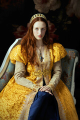 A red-haired woman wearing a historically styled gold gown with puffy sleeves, sitting on an embroidered chaise