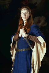 Medieval or high fantasy woman wearing a blue silk dress and holding a dagger