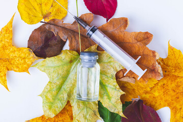 Autumn vaccination of population. Syringe in autumn leaves. Vaccination in autumn. New vaccine..