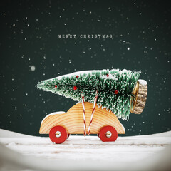 Obraz premium Christmas greeting card design with text. Cute wooden toy car carrying fir tree on the roof. 3D Rendering, 3D Illustration