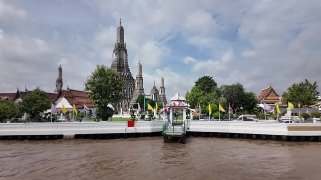 BANGKOK, THAILAND - 1ST OCTOBER 2024: Camera tracks Wat Arun temple from a tour boat on the Chao Phraya River in Bangkok