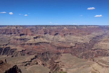 Expansive canyon view with layered rock formations under bright blue sky