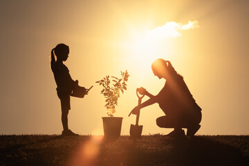 Mother and Child Planting a Tree Together at Sunset – Environmental care, Family Bonding	