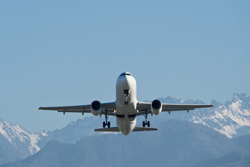 Airplane taking off from the airport against a background of snowy mountains
