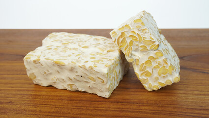 Tempeh or soybean cake, a source of vegetable protein made from boiled soybeans and given yeast through a fermentation process to form a solid, on a wooden cutting board