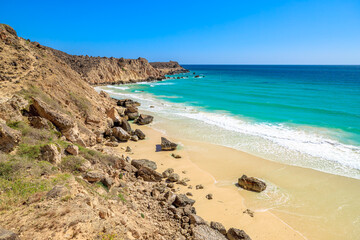 Al Fizayah Beach, at west of Salalah in Oman, is renowned for its stunning white sands, clear waters, and breathtaking rocky cliffs, attracting tourists and locals alike.