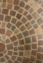 Fan pattern cobblestone pavement in orange and dark red tones with visible mortar joints