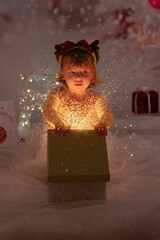 Kleines lachendes M&auml;dchen mit rotem Kleid freut sich &uuml;ber die Weihnachtsgeschenke. 