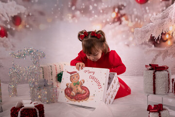 Kleines lachendes M&auml;dchen mit rotem Kleid freut sich &uuml;ber die Weihnachtsgeschenke. 
